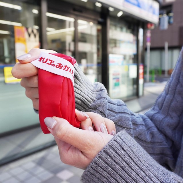 折りたたみエコバッグをコンビニ前で広げようとしている様子